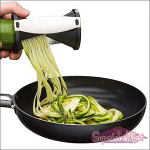 Handheld vegetable spiralizer slicer creating zucchini noodles in a frying pan