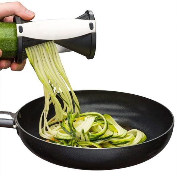 Handheld vegetable spiralizer slicer creating zucchini noodles in a frying pan