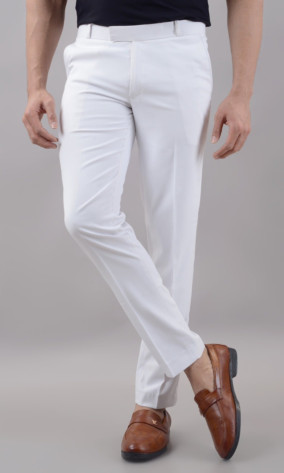 Person wearing white pants and brown shoes on a plain background