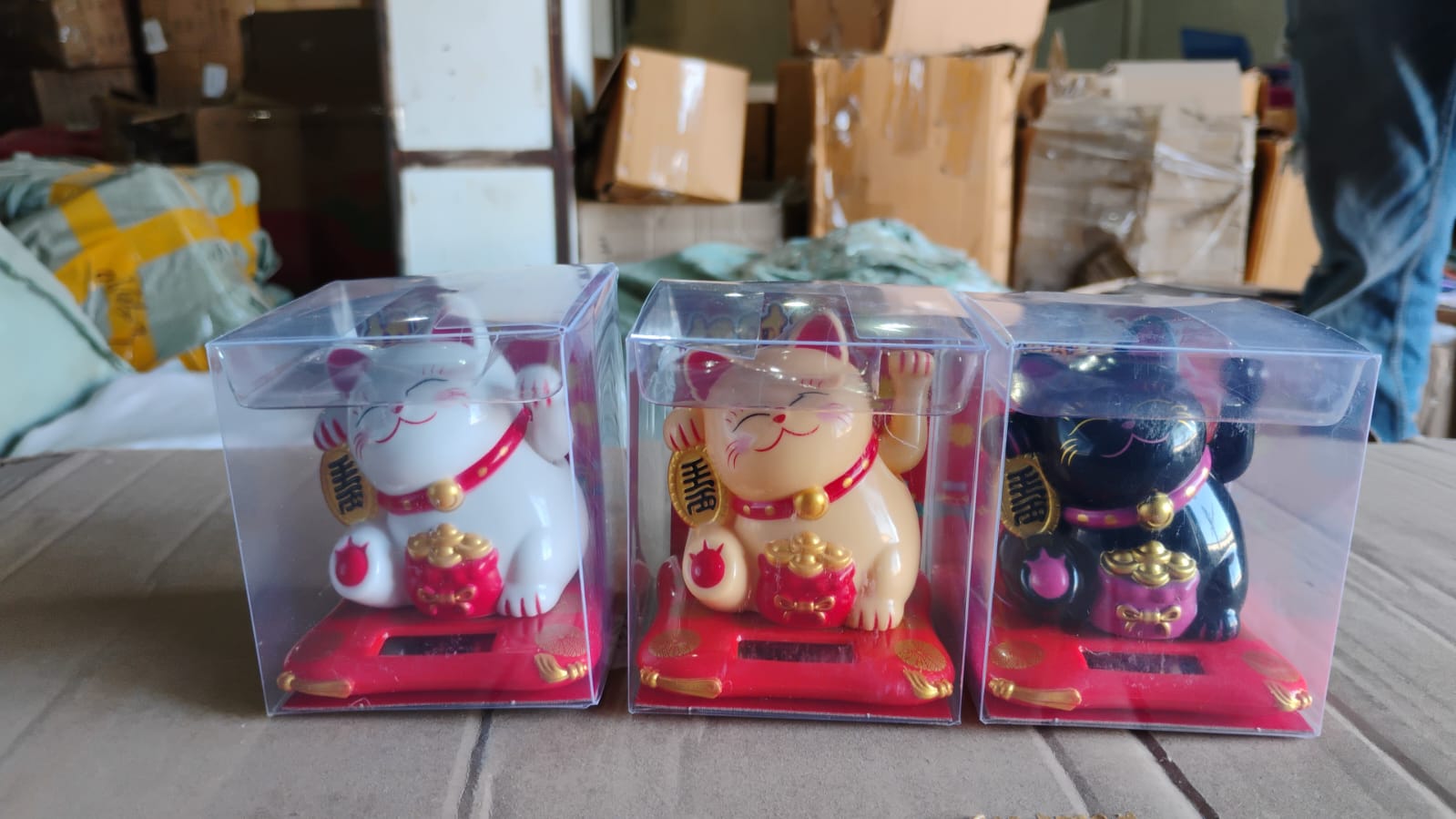 Three color variations of wealth attracting cat figurines in clear boxes for home decor