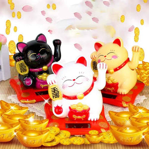 Colorful wealth attracting cat figurines in black, white, and gold on a decorative display with gold coins