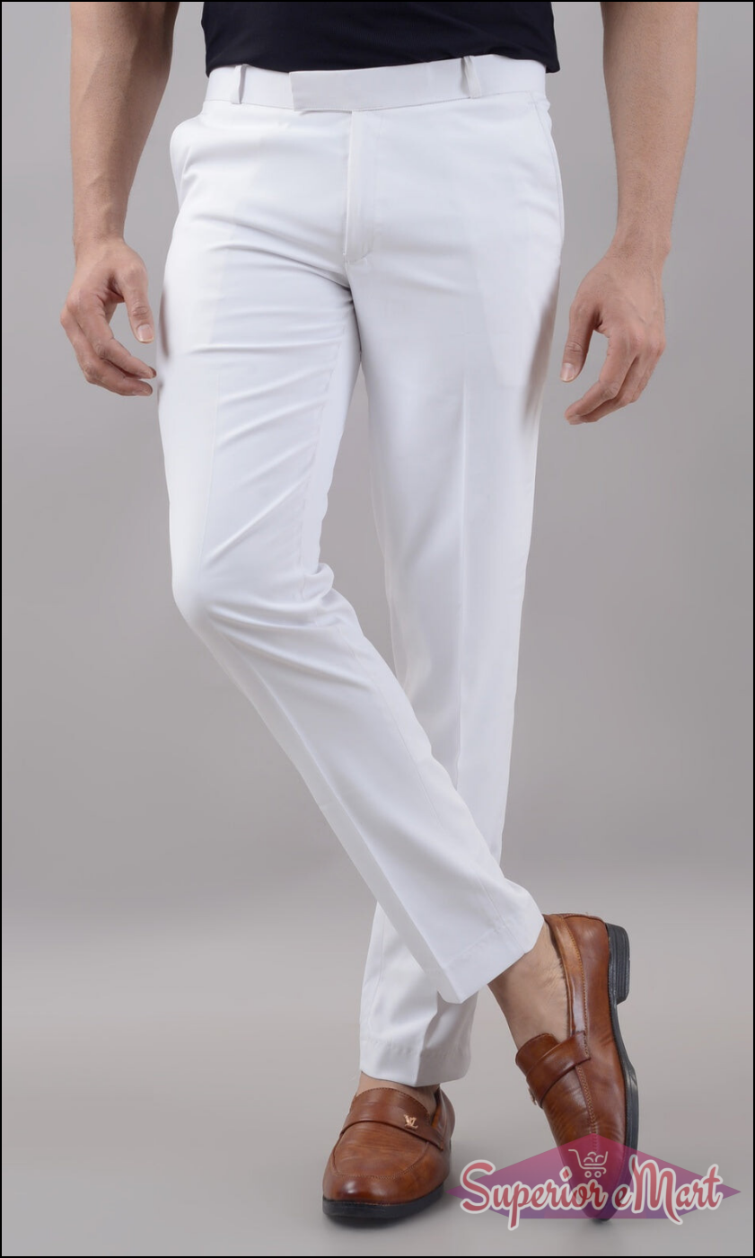 Person wearing white pants and brown shoes on a plain background
