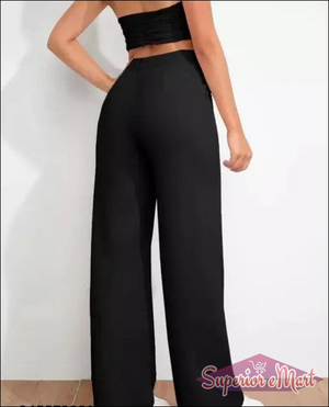 Person wearing black high-waisted pants on a plain background