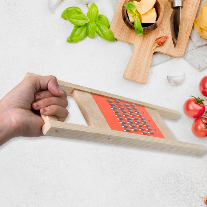Hand holding Superior eMart wooden vegetable grater with metal grating surface on white kitchen countertop